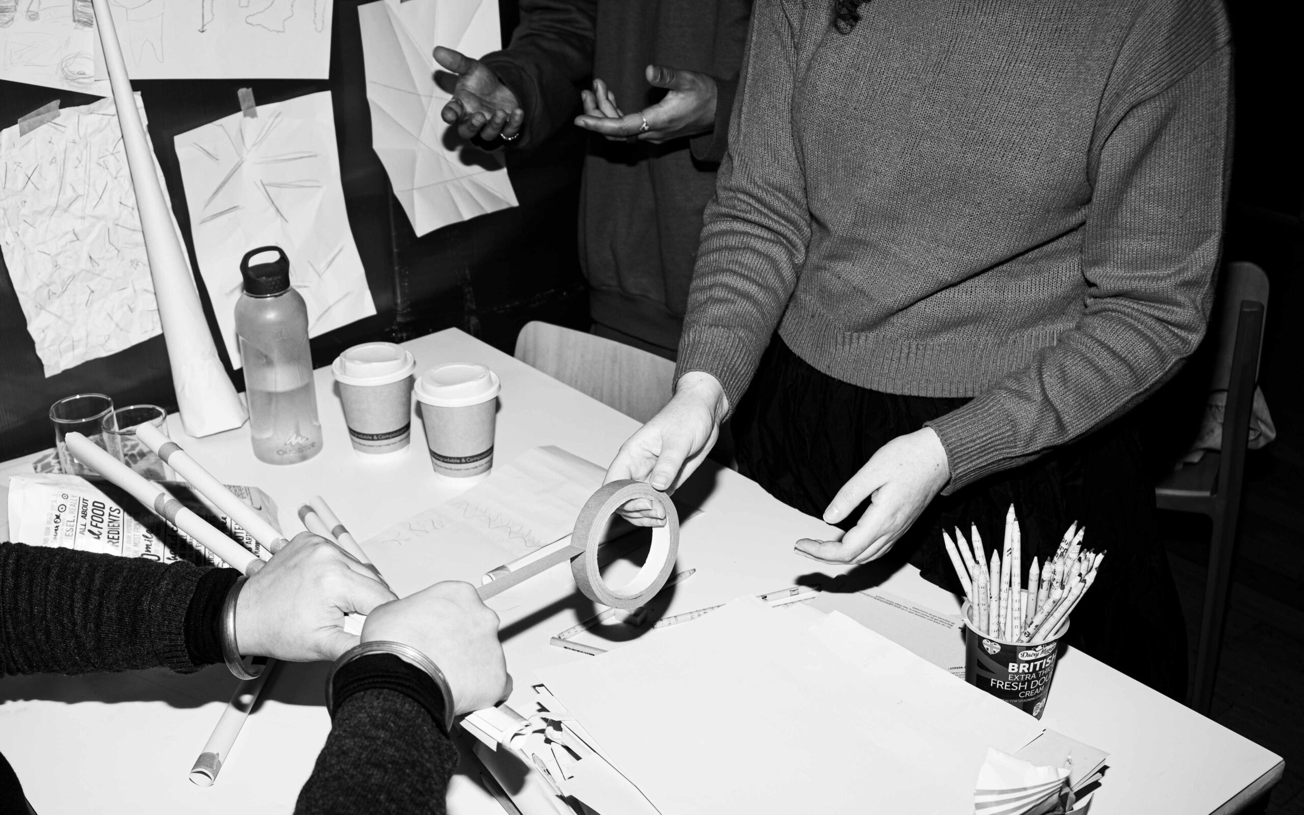 Artists at table making things, only hands are shown.