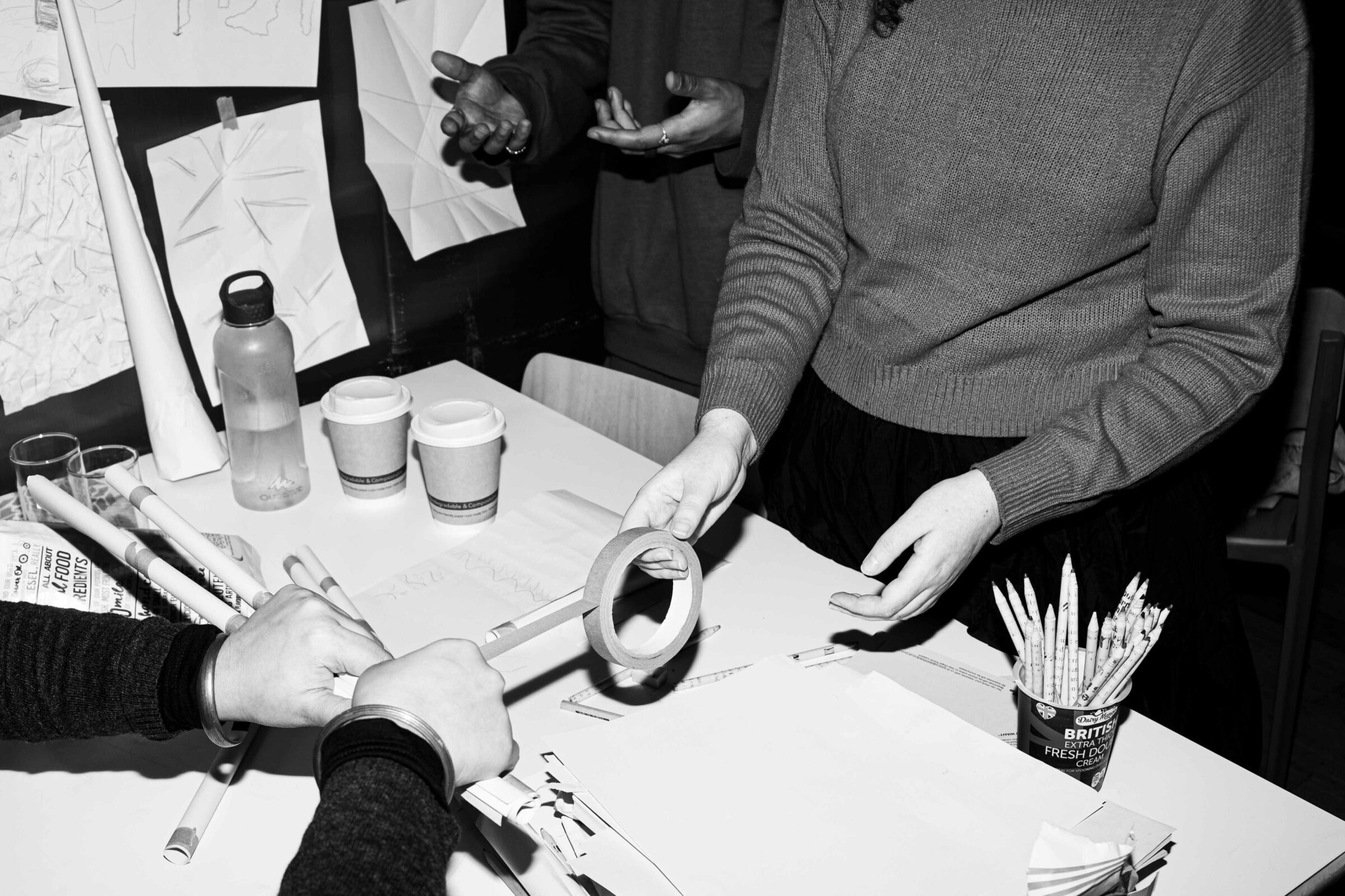 Artists at table making things, only hands are shown.